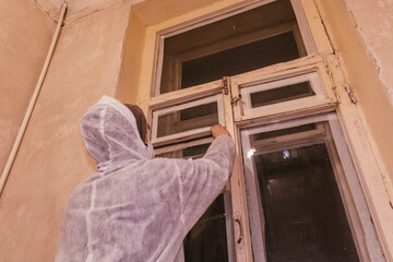 worker painter prepares window to paint masking tape