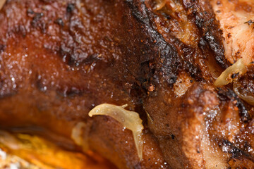 baked meat and fried onions on a baking sheet, pork ham on foil and wooden background, home cooking