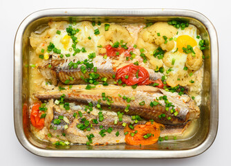 hake fish baked with vegetables close view, baking tray with tomatoes, broccoli and spices, home cooking