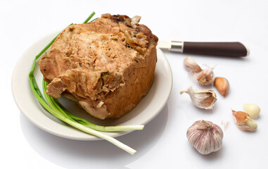 baked meat on a plate, green onion and garlic on white background, home cooking