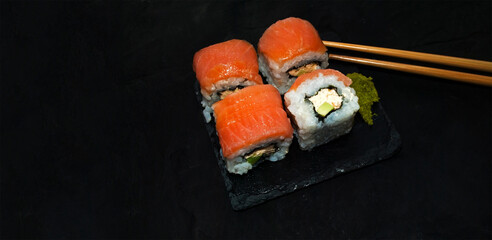 
Close up sushi roll with cream cheese and salmon.Philadelphia.Sushi on stone dark plate on black concrete background with copy space Banner with place for text, copy space.