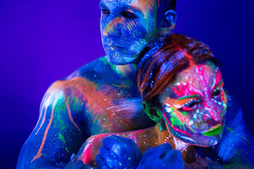 Portrait of a beefy man and woman painted in ultraviolet powder. Body art glowing in ultraviolet...
