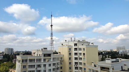 Fototapeta na wymiar Cumulus clouds over city buildings and communication tower antenna in residential district of European city