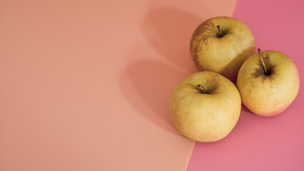 organic yellow apples on the pink background, healthy food. Space for text