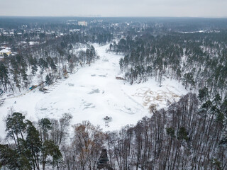 A frozen lake in the middle of a snowy forest. Aerial drone view. Winter snowy morning.