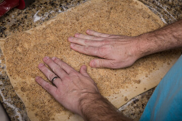 Man's hands pressing filling onto dough rolled out on granite countertop