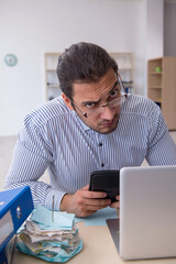Young male bookkeeper calculating tax payments in the office