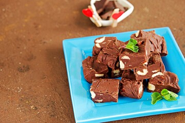 Sliced homemade fudge chocolates made from dark chocolate, condensed milk and hazelnuts on a blue...