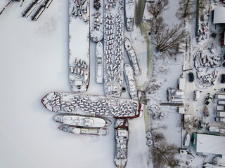 Aerial drone view. Cargo ships in a frozen bay. Cloudy frosty winter day.