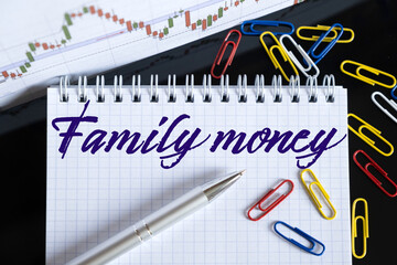 On the desktop are a forex chart, paper clips, a pen and a notebook in which it is written - Family money