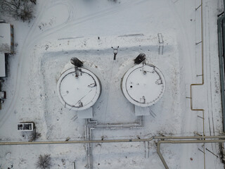 Two tanks with pipes in the industrial area of Kiev. Aerial drone view. Winter snowy day.