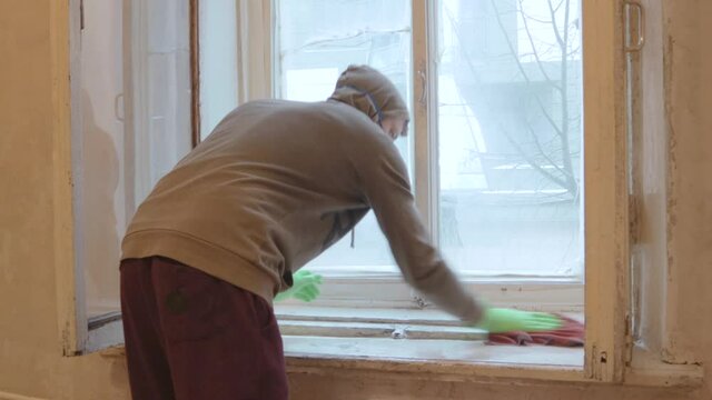 man worker clean window wooden frames in gloves and mask