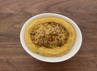 A combination of two types of mustard in a white bowl