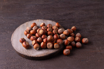 Hazelnuts on a round wooden board on a blue background. Horizontal orientation. 