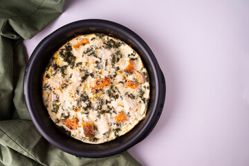 Casserole with salmon, eggs, cabbage, cream in a round frying pan. Horizontal orientation. View from above.