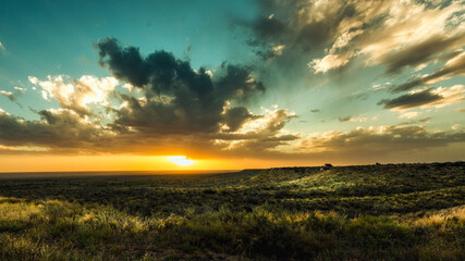 Obraz premium Panoramic of the sunset during the golden hour with landscape of Patagonian plateau and partly cloudy sky