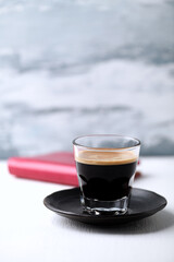 Coffee in glass cup on bright wooden background.