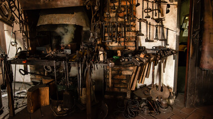 Interior of Blacksmith forge with tools hanging on wall and anvil and hammer ready to be used. Furnace formant
