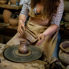Creating a jar or vase Master crock. The sculptor in workshop makes jug out of earthenware closeup. artisan woman makes a pot on a potter's wheel from clay close-up
