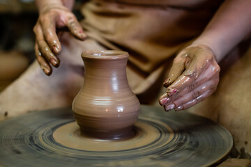Creating a jar or vase Master crock. The sculptor in workshop makes jug out of earthenware closeup. artisan woman makes a pot on a potter's wheel from clay close-up