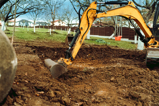 Landscaping works in the home garden at construction site with mini yellow excavator