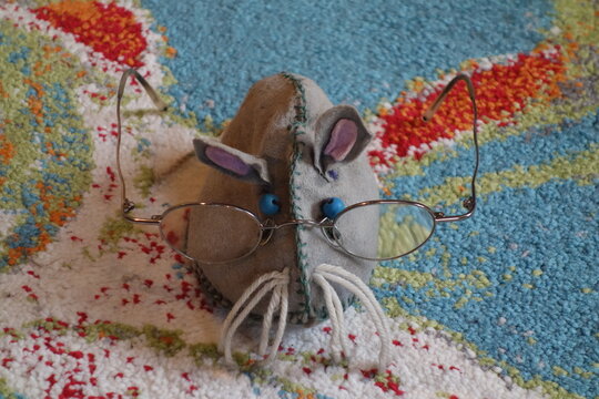 Belesene intelligent aussehende Stofftier Maus mit vielzu gro&szlig;er altmodischer Brille und treuen blauen Glubschaugen.