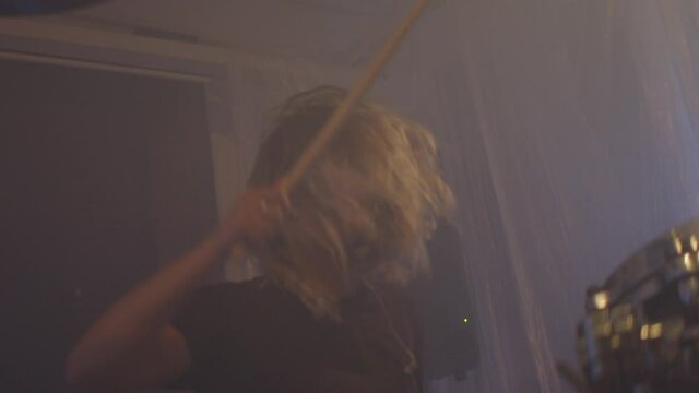 young caucasian girl plays the drums very aggressively. a reference to the Whiplash movie. A furious and angry blonde plays heavy music. hitting musical cymbals with sticks