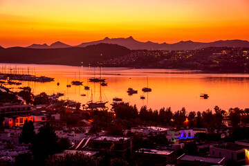 Fototapeta premium A red dawning for us as a seaside village bay with yachts.