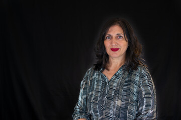 Portrait of Spanish brunette woman with long hair on black background and red lips