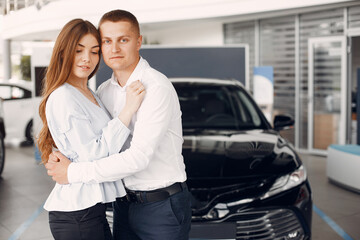 Fototapeta na wymiar Couple in a car salon. Family buying the car. Elegant woman in a white blouse