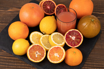 Sliced lemon and grapefruit with freshly squeezed grapefruit juice on black slate