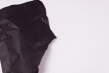 one sheet of black crumpled paper lies on the left side of the frame