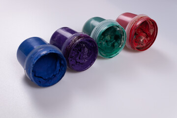 blue, orange, green and red cans of gouache paint lie on the side diagonally