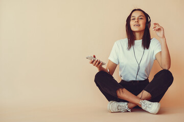 Girl with headphones. Lady on a yellow background. Woman in a white t-shirt.