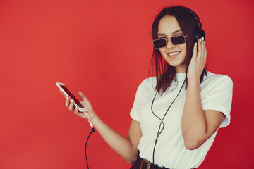 Girl with headphones. Lady on a red background. Woman in a white t-shirt.