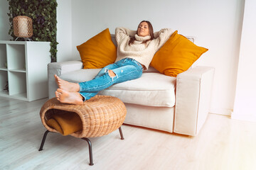 Calm satisfied and relaxed woman in cozy sweater resting or sleeping on the sofa in the living...