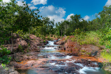babbling brook long exposure in the national forest of australia surrounded by red rocks and lush grasslands