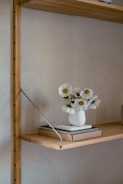 wei&szlig;e Blumen (Kosmeen) in wei&szlig;er Vase in Regal 