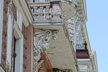 part of the brown concrete wall of a historic building and a white balcony with sculpture