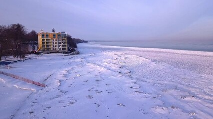 Slowly climbing over stacks of ice shove along the city's frozen shoreline.