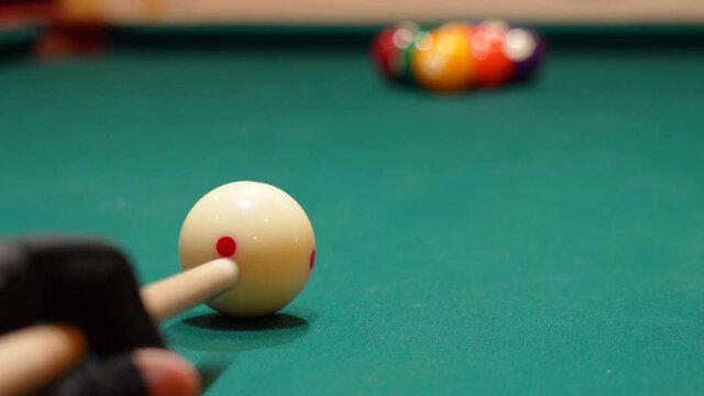 Low Angle Closeup of Cue Ball as Person Wearing Glove Breaks Rack of 9 Ball Powerfully on a Pool Table with Green Felt and the Cue Stick Bending as Both Solid and Stripe Balls Scatter, No Faces in Bar