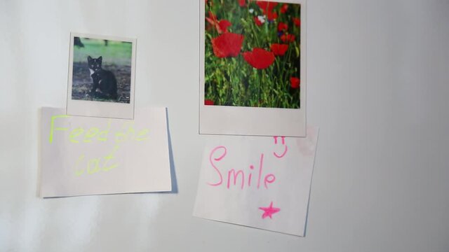 The man's hands hang magnets with a note on the surface of the refrigerator.