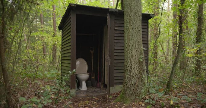 Outdoor toilet in the woods. Restroom in a wooden shed in a forest.Outdoor toilet in the middle of a forest. Outhouse between the trees. A dated lavatory in nature. WC in woodlands. Toilet in a shack.