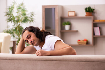 Young lazy man in oversleeping concept at home