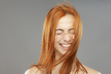 Happy red hair girl smiling. Studio portrait on gray background