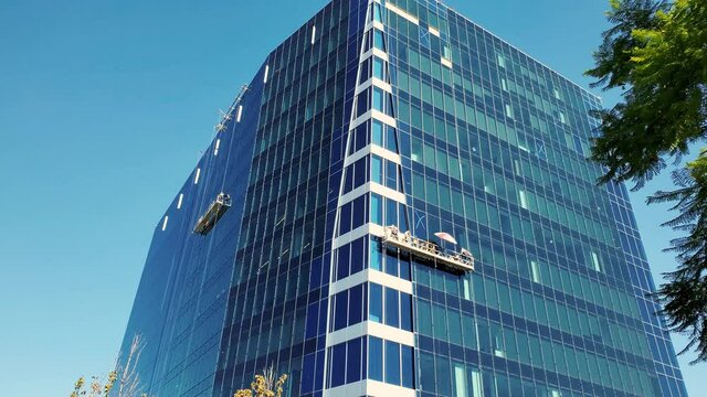 An office building gets window cleaning from workers on a high swing stage suspended scaffold.