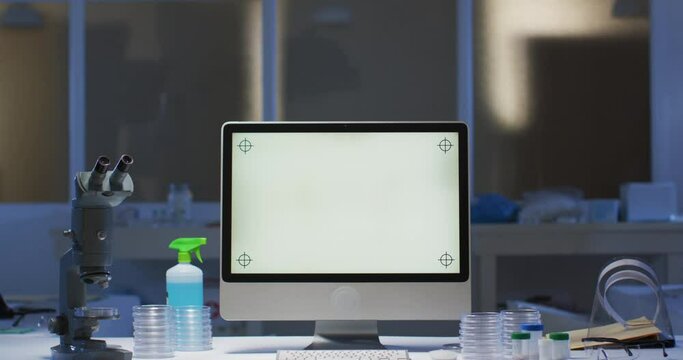 Desktop computer with illuminated screen at a workstation in an empty laboratory