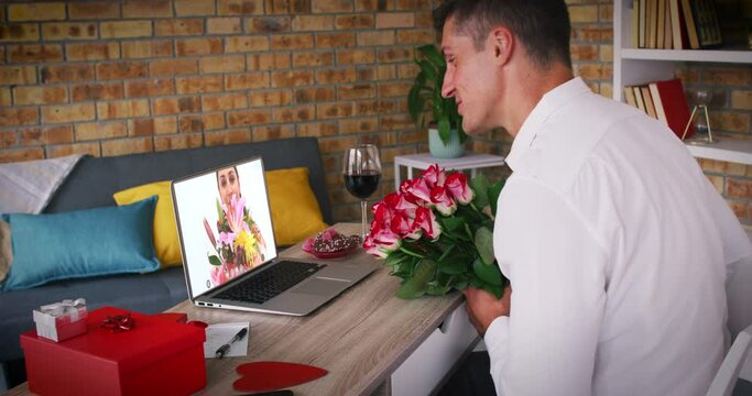 Caucasian couple holding flowers making valentines date video call man blowing kiss to woman on lapt