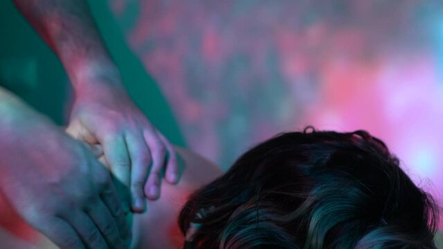 Physiotherapist with ambient light in spa working contractures on woman's neck