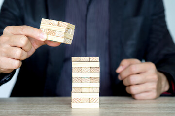 Steps of success for business or investment. Business man is arranging wood block to increase high,...